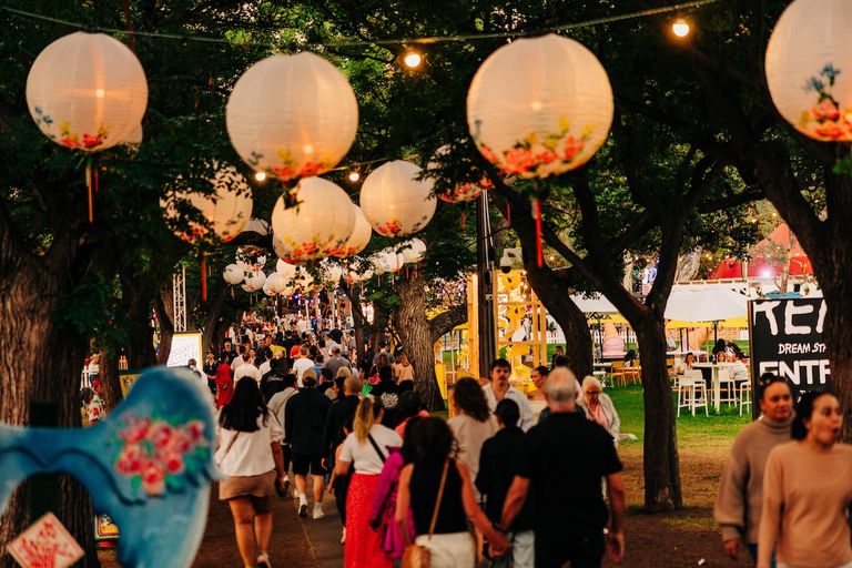 Crowds walking beneath glowing paper lanterns and string lights at The Garden of Unearthly Delights festival venue in Adelaide.